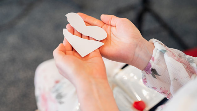 A paper heart broken, being held by a woman
