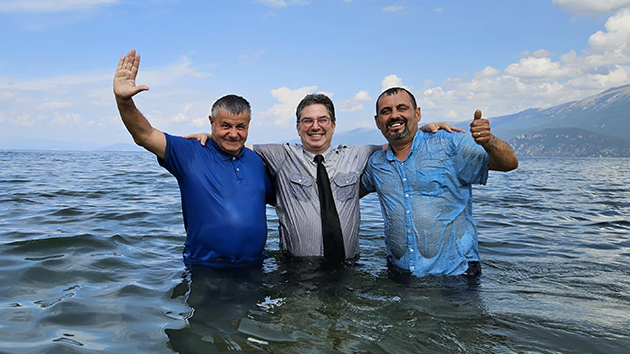 Pastor Gentian Thomollari baptises Spiro Ndrio and Eugen Cela in the waters of Lake Ohrid, Albania, with Ndrio, Gentian and Cela pictured from left to right
