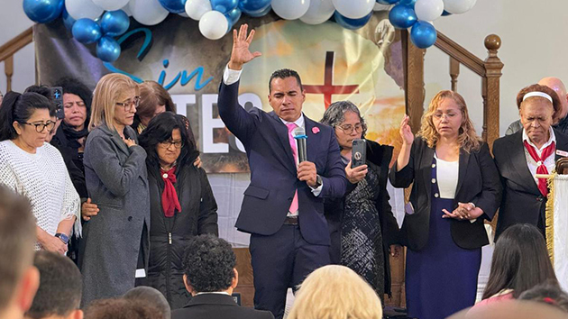 Pastor José Saavedra prays with individuals committing their lives to Jesus during the closing service