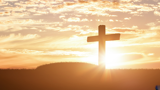 A cross stands silhouetted against the sunrise, reflecting the hope of the resurrection at the heart of Easter