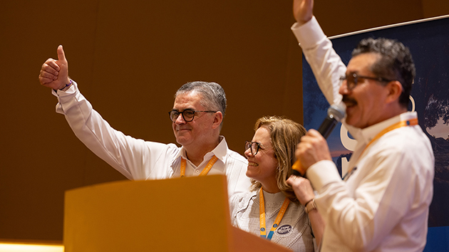 General Conference President Pastor Erton C Köhler and his wife, Adrienne, smile as IAD President Pastor Abner De los Santos (right) raises his hand in appreciation following Köhler’s devotional message. The couple received a token of gratitude before departing for their next engagement